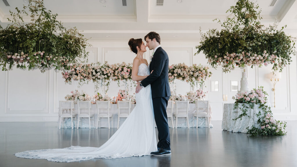 bride and groom kiss in their reception hall surrounded by flowers