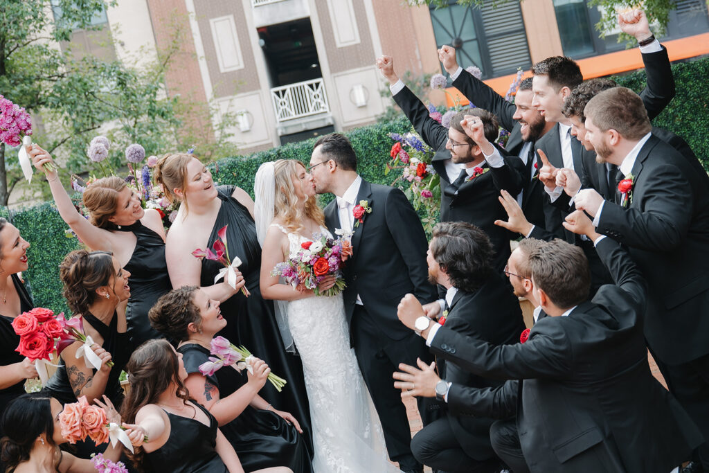 bridal party cheering for the bride and groom kissing at their cocktail hour