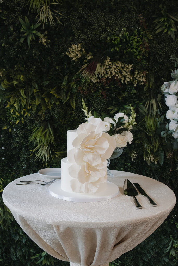 wedding cake table in front of greenery